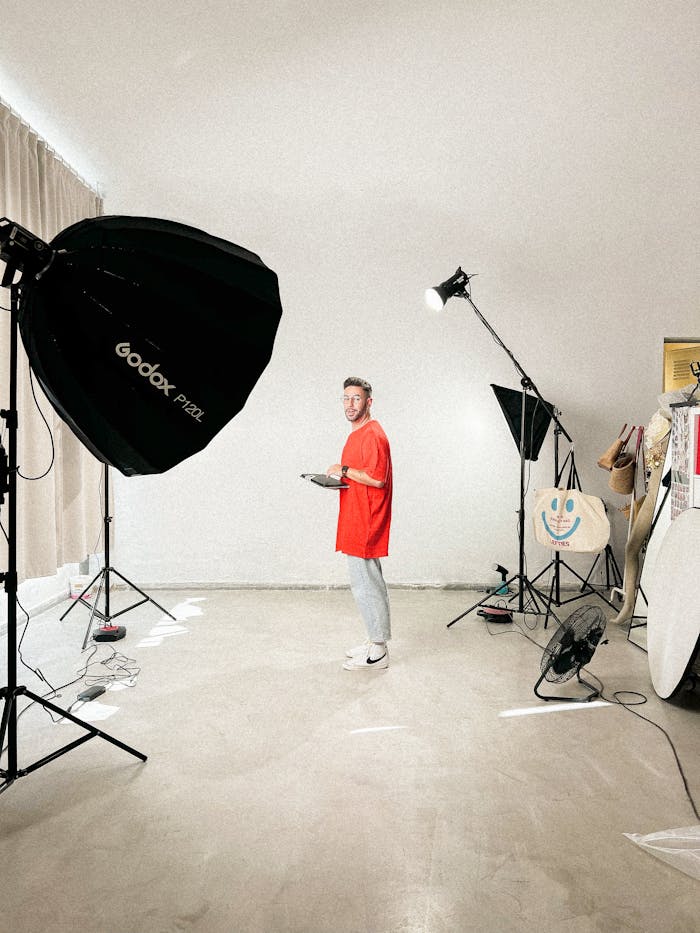 Man in red shirt in a bright studio setup with lighting gear.